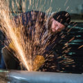 Sparks from a grinder as operator works on building farm machinery